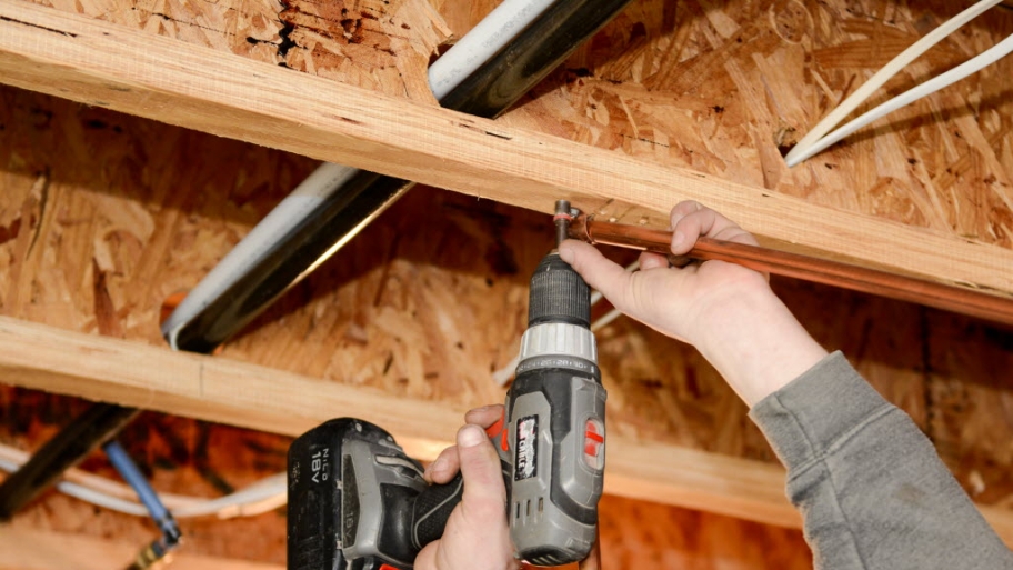 Plumber's hands installing pipe with screwdriver